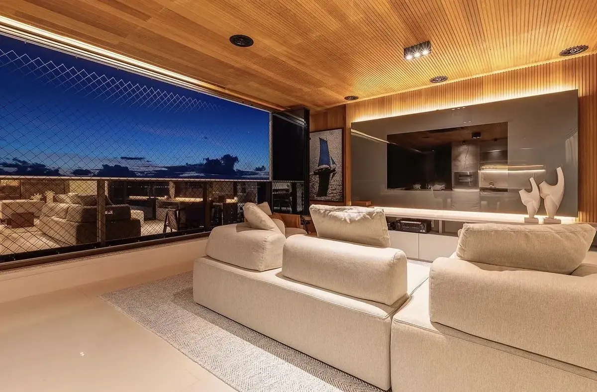 Sala de estar com vista para o mar, home theater e iluminação em sanca