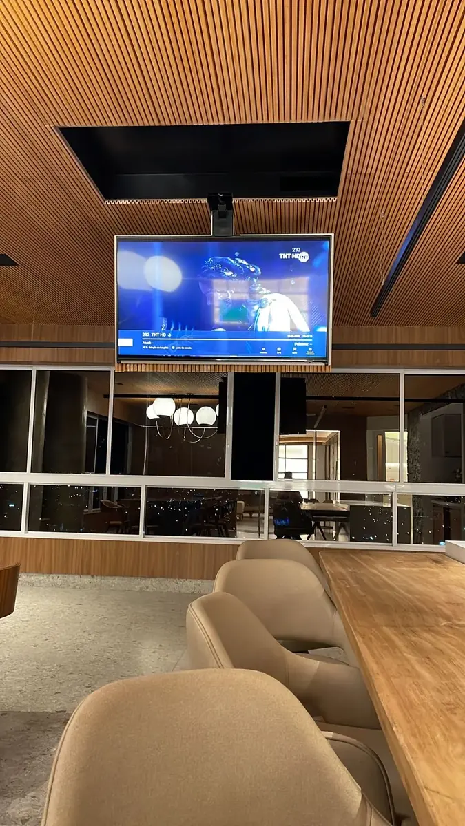 TV descendo do forro de madeira em espaço gourmet